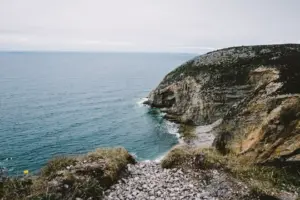 Falaise rocheuse dominant la mer sur une côte sauvage.